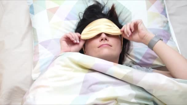 Top view on the young woman wearing sleep mask preparing for sleep, daytime sleep and relaxation. Lifestyle and people concept. Self isolation, home quarantine, social distancing. - Πλάνα, βίντεο