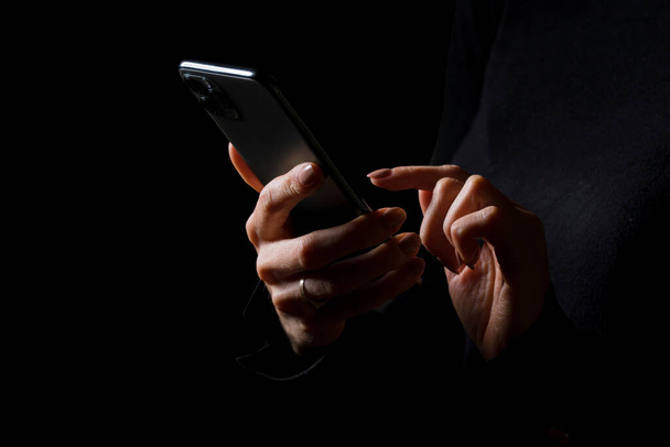 Person holding in hands and typing on mobile phone, photo isolated on black background - Foto, Imagen