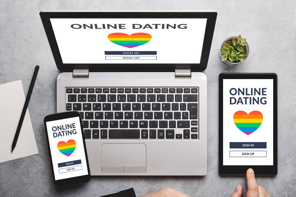 LGBT namoro conceito de aplicativo no laptop, tablet e tela do smartphone sobre mesa cinza. Gay namoro online. Depósito plano
 - Foto, Imagem
