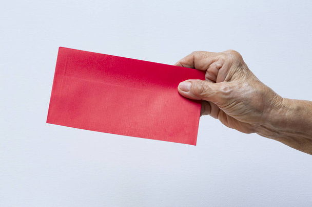 La mano derecha de la mujer mayor sosteniendo sobre rojo en fondo blanco aislado, Primer plano, Feliz año nuevo concepto chino
 - Foto, imagen