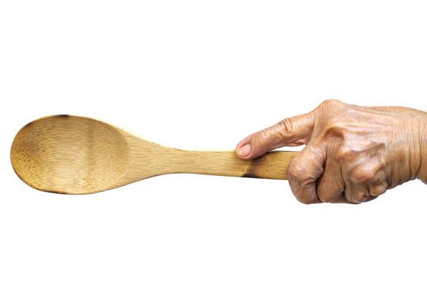 Mão esquerda da mulher sênior segurando concha de madeira no fundo branco, Close up shot, Foco seletivo, Utensílios de cozinha conceito
 - Foto, Imagem