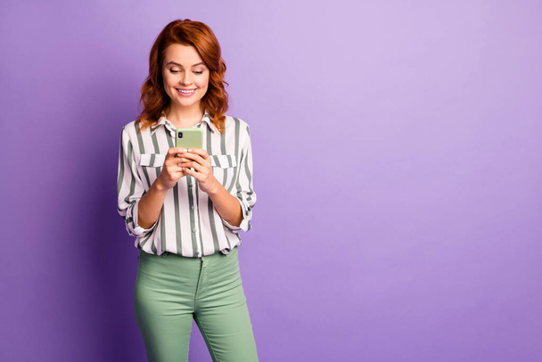 Portrait of positive cheerful woman use smart phone read social network information wear good look clothes isolated over violet color background - 写真・画像