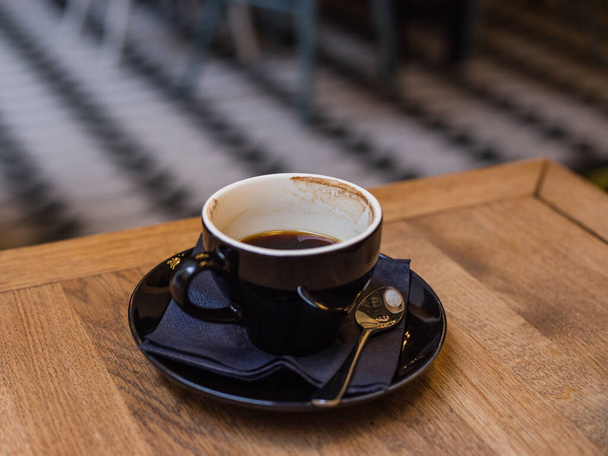 Una taza de café expreso medio lleno en la mesa de madera por la mañana
 - Foto, imagen