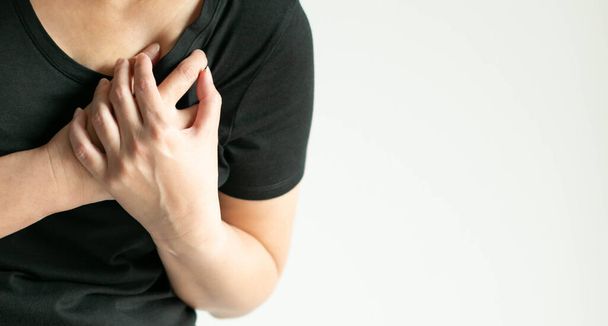 Close-up of a woman pressing on left chest with painful on white background with copy space. the concept of heart attack patient, health care and medical. - Photo, Image
