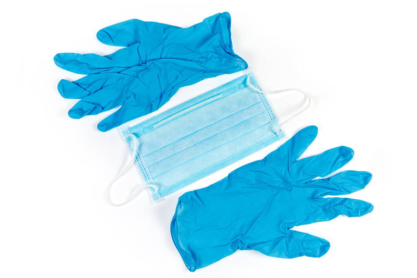 Kék eldobható orvosi arcmaszk és nitril pormentes orvosi kesztyű fehér alapon, felülnézetből - Fotó, kép