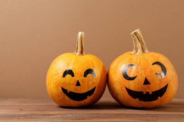Kürbisse mit aufgemalten Gesichtern auf farbigem Hintergrund zu Halloween. - Foto, Bild