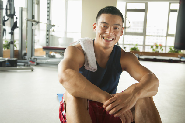 νεαρός άνδρας κάθεται στο γυμναστήριο - Φωτογραφία, εικόνα