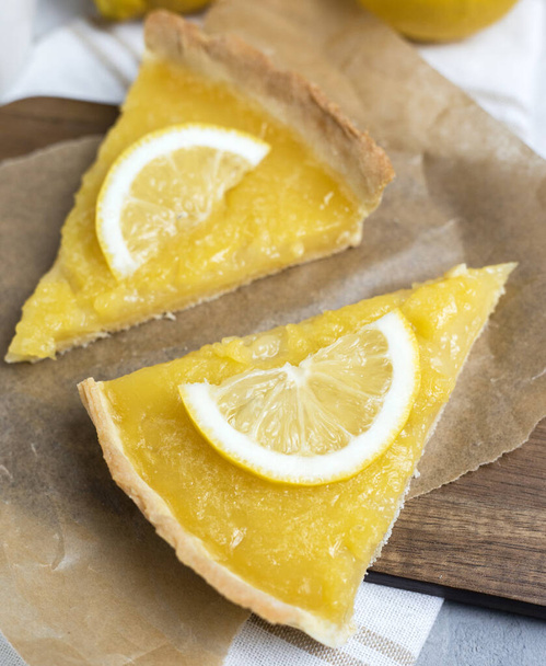 two pieces of lemon tart with slice of lemons closeup on stone background - Photo, Image