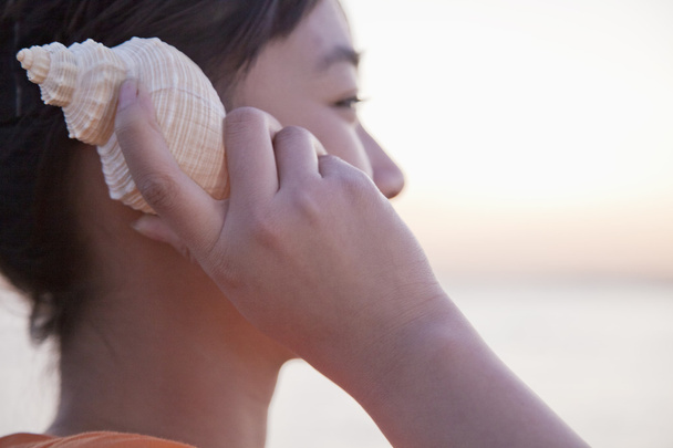 Adolescente escuchando concha marina
 - Foto, imagen