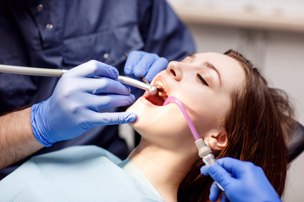Dentista che cura i denti a una giovane paziente in clinica
. - Foto, immagini