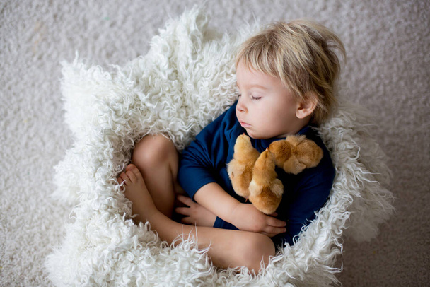 Cute blond toddler boy, sleeping with newborn chicks, hugging them tenderly - Photo, image