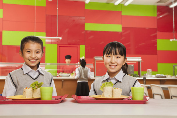 twee meisjes zitten in Schoolcafetaria - Foto, afbeelding