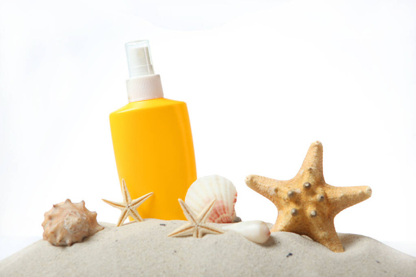 песок, раковины, морская звезда и солнцезащитный крем изолированы на белом. Защита кожи от солнца
. - Фото, изображение