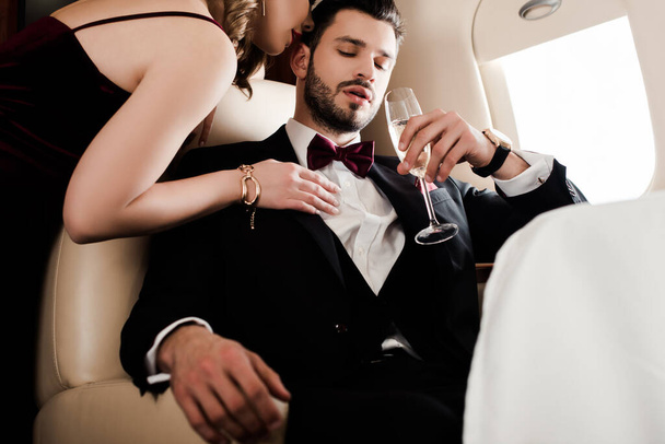 cropped view of seductive woman touching elegant, confident man holding glass of champagne - Photo, Image