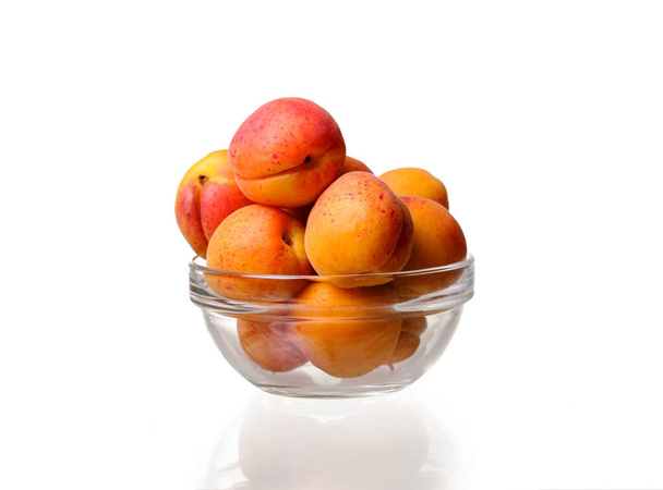 glazen schaal met abrikozen op een witte ondergrond. idee en concept van gezonde en juiste voeding, biologische producten - Foto, afbeelding