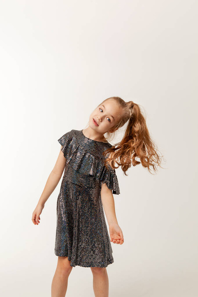 klein meisje in pailletten jurk is dansen - Foto, afbeelding