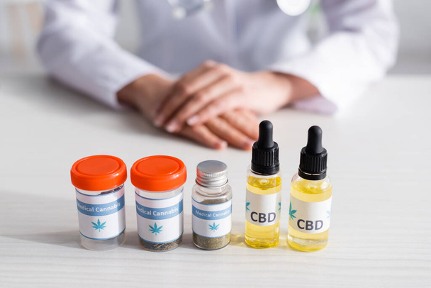 selective focus of bottles with cbd and medical cannabis lettering near doctor  - Photo, Image