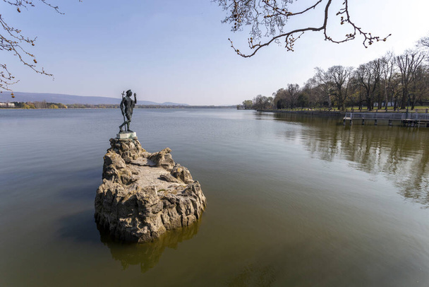 El viejo lago en Tata, Hungría con la estatua de San Juan en un día de primavera
. - Foto, Imagen