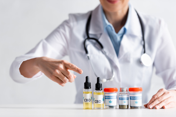 cropped view of doctor pointing with finger at bottles with cbd lettering  - Foto, Imagem