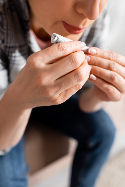 cropped view of mature woman blowing on joint with legal marijuana at home  - Photo, Image