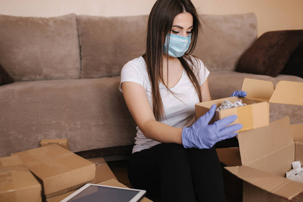 Žena v karanténě nosí doma ochrannou masku a nakupuje online. Koncept koronaviru. Zůstaň doma - Fotografie, Obrázek