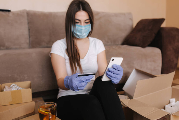 Жінка в карантині носить захисну маску вдома і купує онлайн. Концепція Коронавірусу. Залишайтеся вдома - Фото, зображення