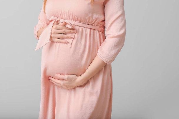 Bella donna incinta su sfondo grigio - Foto, immagini