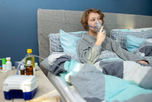 Genç bir kız evde nefes alıp veriyor, genç bir kadın evinde nebulizatörle nefes alıyor. - Fotoğraf, Görsel
