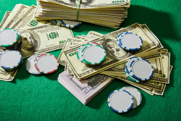 Vysoký úhel pohledu na dolarové bankovky a žetony kasina na zeleném pozadí - Fotografie, Obrázek
