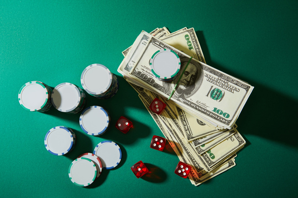 Top view of dollar banknotes, dice and casino tokens on green background - Photo, Image