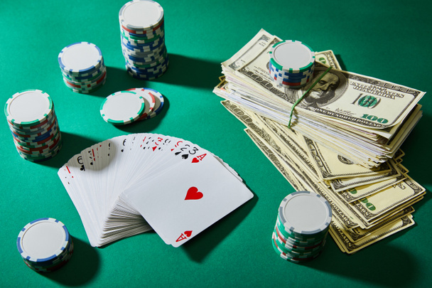 High angle view of playing cards, casino tokens and dollar banknotes on green  - 写真・画像