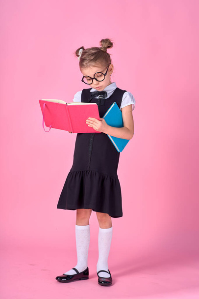 Cute little girl with glasses and books on pink background, space for text. Reading concept - Foto, Imagen