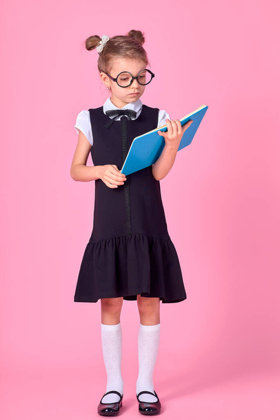Cute little girl with glasses and books on pink background, space for text. Reading concept - Foto, afbeelding