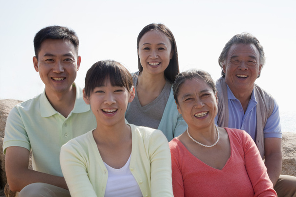 "Портрет усміхненої багатоповерхової сім'ї, що сидить на скелях на відкритому повітрі
 - Фото, зображення