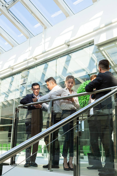 young business people are standing and talking on the background of glass offices. Corporate businessteam and manager in a meeting. - Foto, Imagem