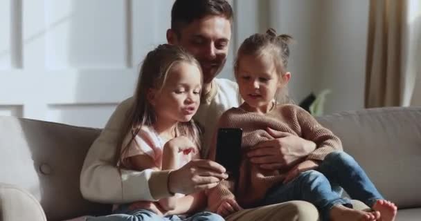 Papá sonriente mostrando aplicaciones móviles educativas a niños pequeños
. - Metraje, vídeo