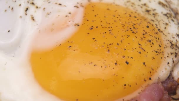 Zlatý žloutek makro výstřel. Bio kuřecí vejce se slaninou, smažené na pánvi s pepřem a solí - Záběry, video