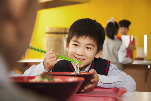 School boy eats noodles in school cafeteria - Foto, Imagen