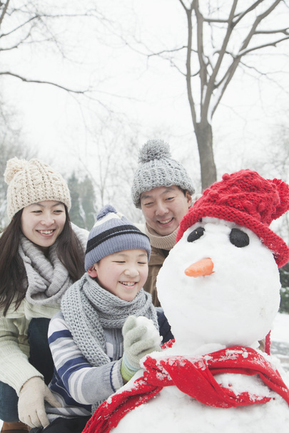 Familia haciendo muñeco de nieve en invierno
 - Foto, Imagen