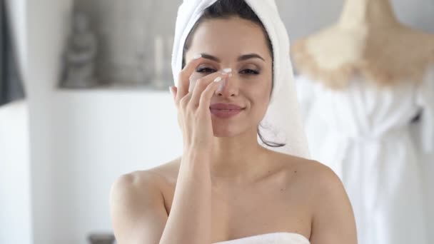 Close-up portrait of attractive woman applying cream on the face after shower. Handheld shot. - Felvétel, videó