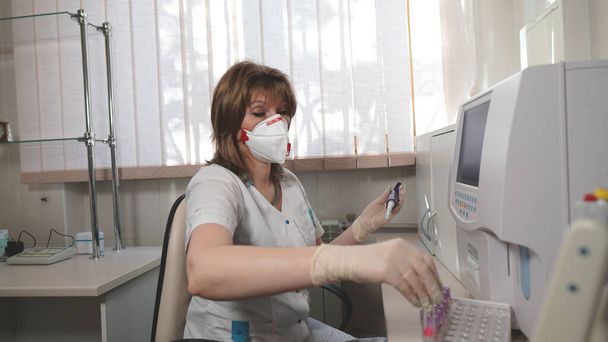 Egy orvosi laboratóriumi technikus portréja vörös szelepes lélegeztetőgéppel a koronavírusból egy laboratóriumban vizsgálatra. - Igen. Laboratóriumi technikus, aki a pipettát tartja és vérmintákat vizsgál. - Fotó, kép
