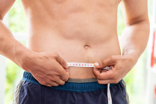 Torso masculino muscular con cinta métrica, pérdida de peso y concepto de dieta
 - Foto, Imagen