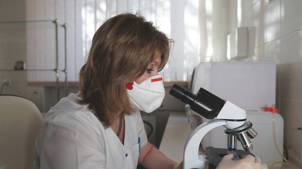 Fiatal nő a lélegeztetőgépben professzionális labortechnikus, aki orvosi laboratóriumban vizsgálja a mikroszkóp szemhéját, koronavírus járvány. - Fotó, kép