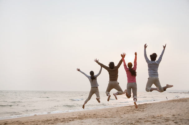 Ystävät hyppäävät rannalla
 - Valokuva, kuva