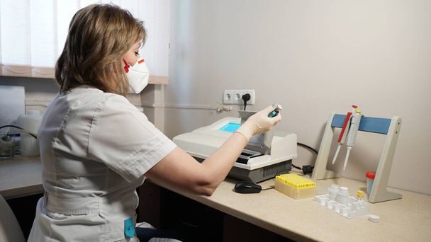 調査のための研究室でコロナウイルスから赤いバルブマスクを持つ医療研究室の技術者の肖像。そうだ。ピペットを保持し、血液サンプルをテストするラボ技術者 - 写真・画像
