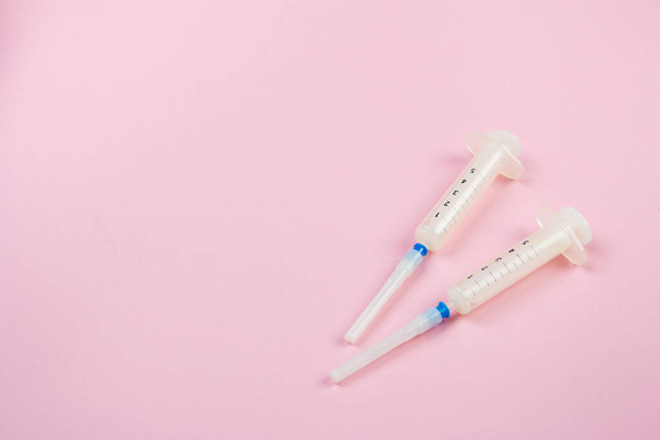 Two medical syringes lie on a pink background - Foto, imagen
