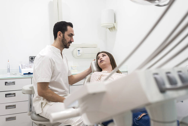 Der bärtige Zahnarzt erklärt einer Patientin das Verfahren - Foto, Bild