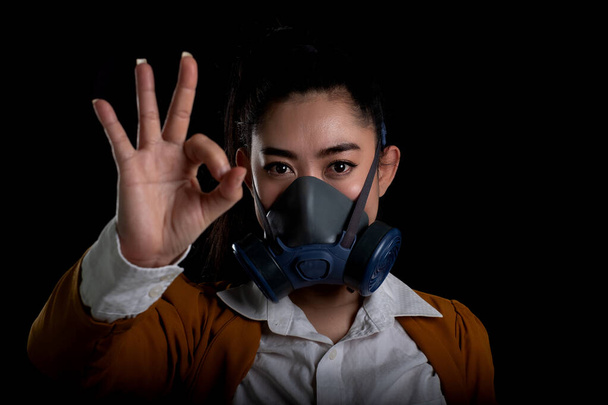 Mujer de negocios de la joven mujer de Asia que se pone un respirador máscara N95 para proteger de las enfermedades respiratorias transmitidas por el aire como la gripe covid-19 coronavirus PM2.5 polvo y smog, Señal de mano de las mujeres o.k
 - Foto, Imagen