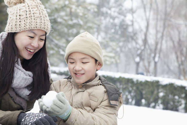 Madre ayudando hijo hacer bola de nieve
 - Foto, Imagen