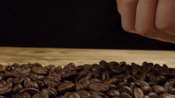 Ręka kobiet rozrzuca ziarna kawy na stole - Materiał filmowy, wideo